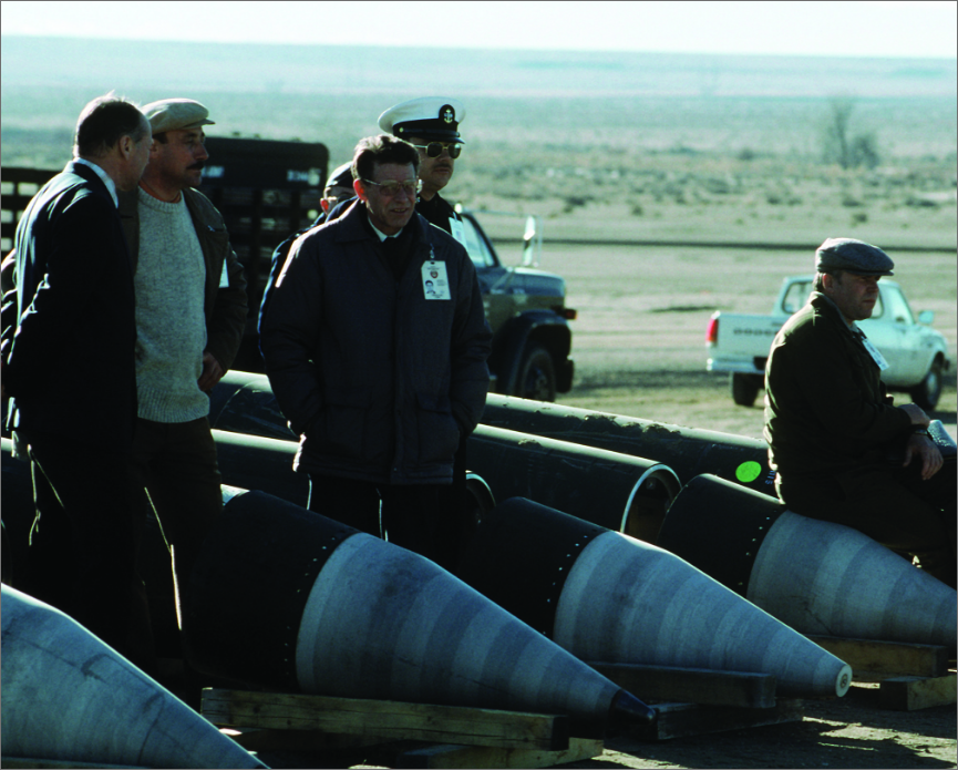 Men standing in desert next to disarmed cruise missiles